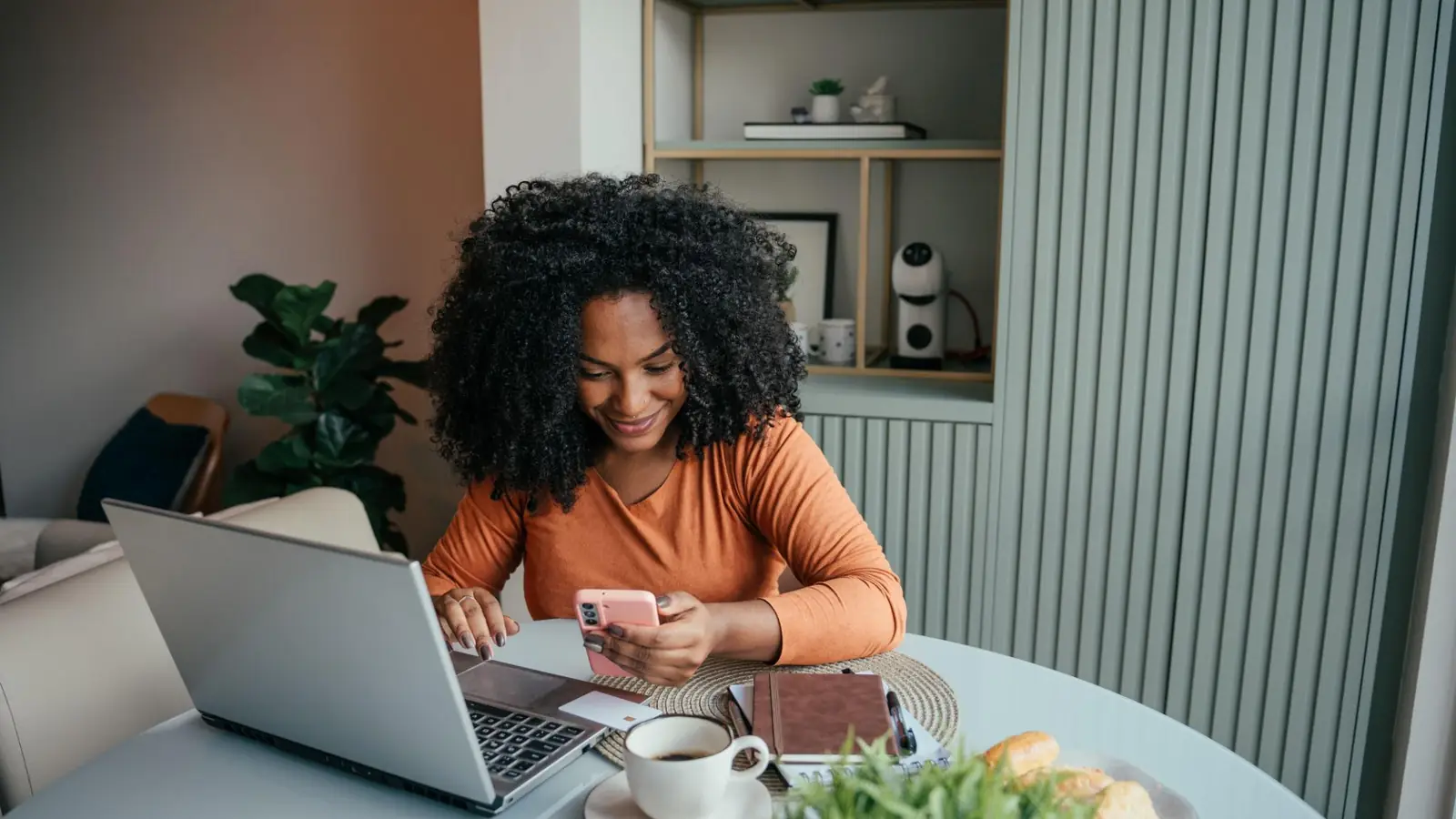 Comércio agêntico: consumidora usa celular e notebook para fazer compras online